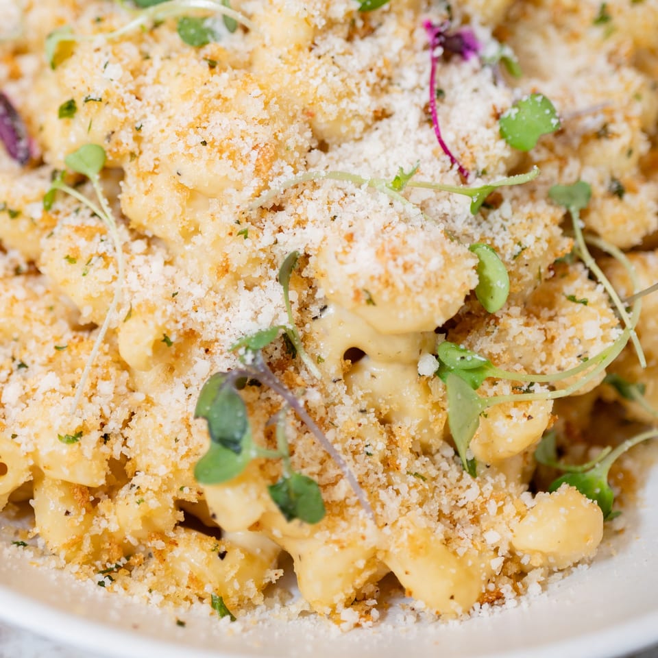 Close-up of vegan mac and cheese topped with breadcrumbs and microgreens.