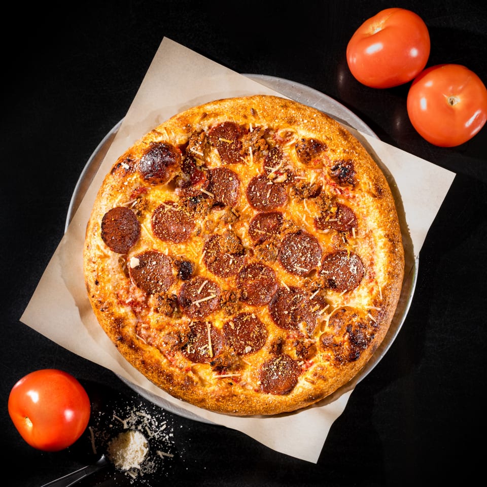 Down 2 Earth Pizzeria's vegan pepperoni and sausage pizza with tomatoes and grated cheese.